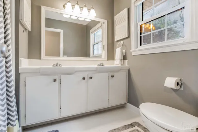 a bathroom with a granite countertop toilet sink and mirror