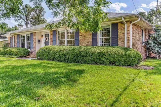 a view of a brick house with a big yard and potted plants