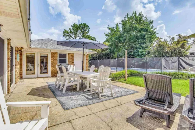 a view of a patio with table and chairs potted plants and a large tree