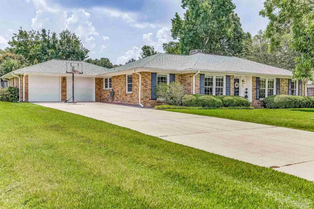 a front view of a house with a garden and trees