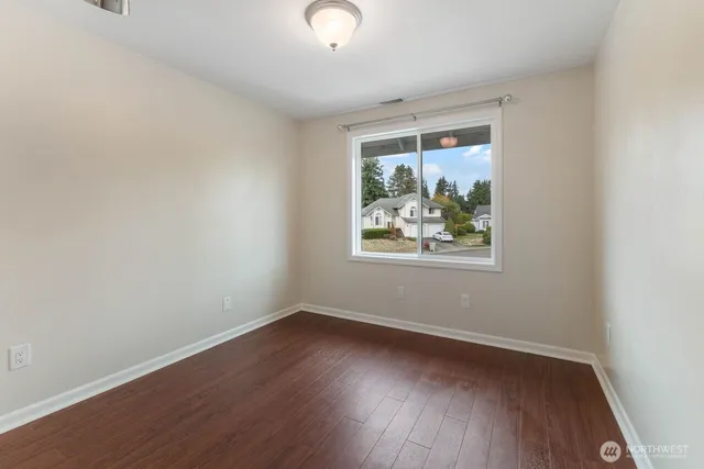 an empty room with wooden floor and window