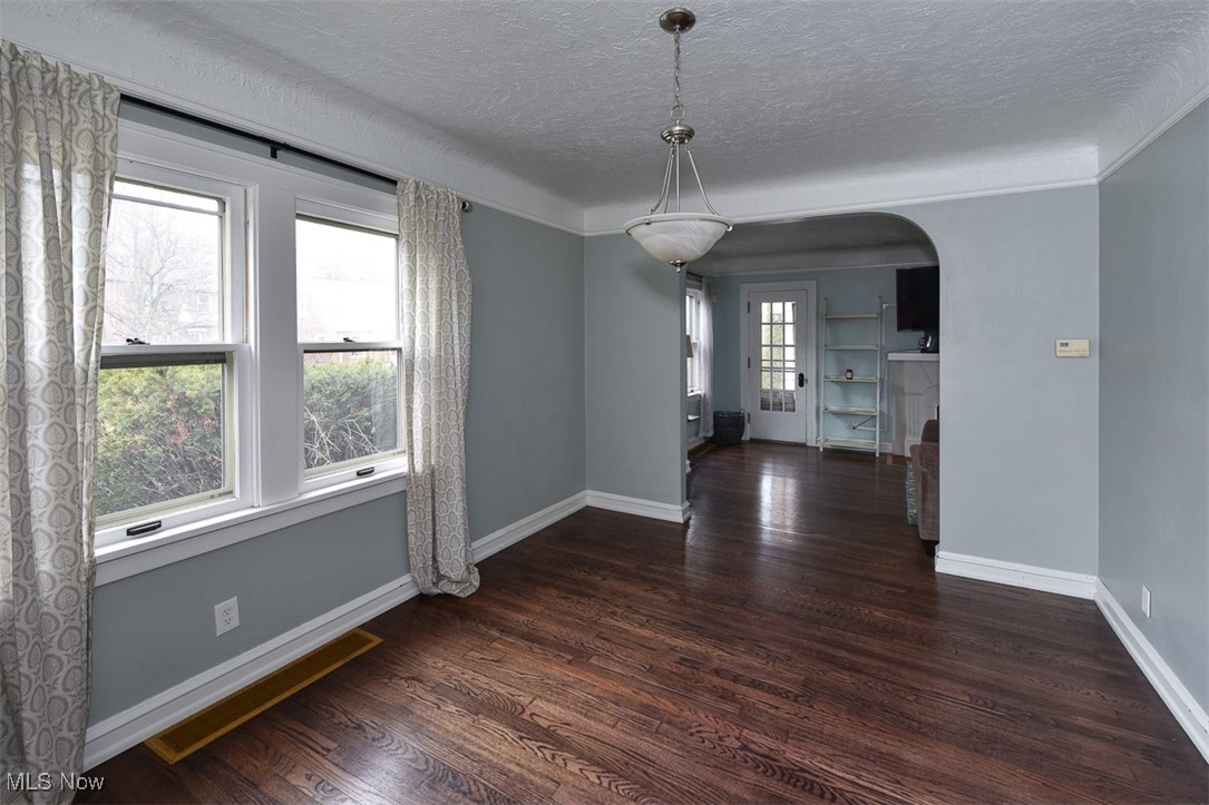999 Pennfield Road Cleveland, OH 44121 - Photo 7 of 42 Unfurnished dining area featuring dark hardwood / wood-style flooring and a textured ceiling
