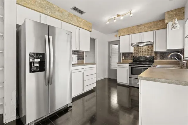 a kitchen with a refrigerator sink and cabinets