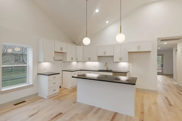 a kitchen with stainless steel appliances granite countertop a sink a stove and a wooden floors