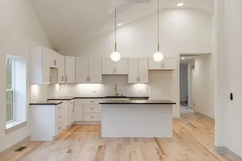 a large kitchen with granite countertop a sink cabinets and wooden floor