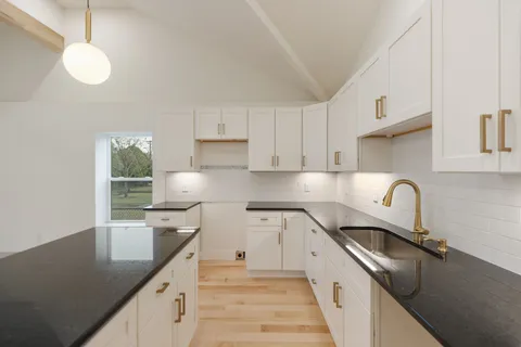 a kitchen with granite countertop a sink a stove and cabinets