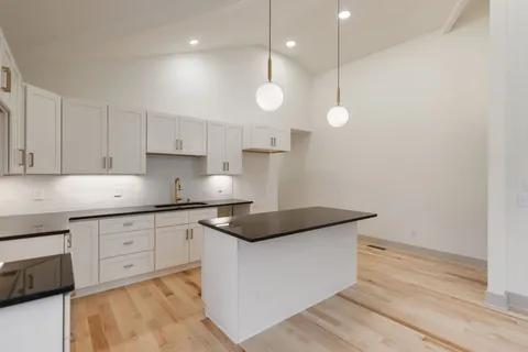 a kitchen with a sink dishwasher and white cabinets with wooden floor