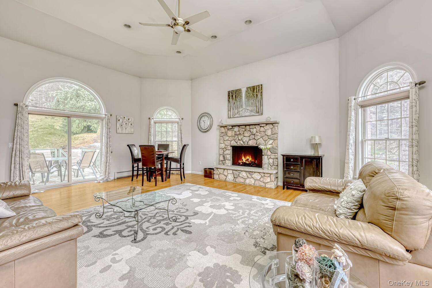 22 Golden Road Suffern, NY 10901 - Photo 15 of 41 Living room with a stone fireplace, light wood-type flooring, ceiling fan, plenty of natural light, and a high ceiling