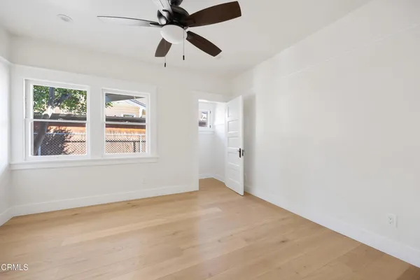 an empty room with windows and fan