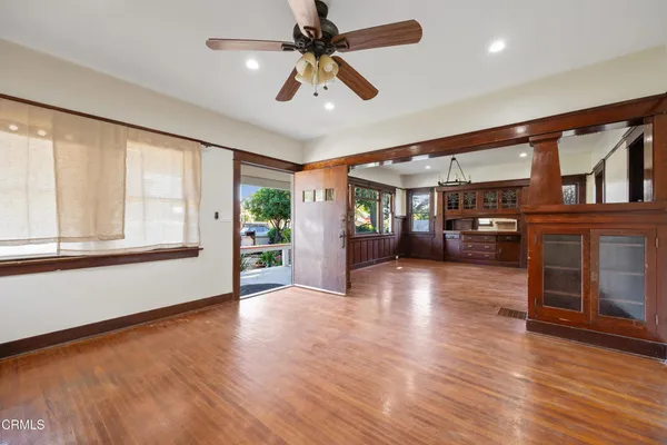 an empty room with wooden floor chandelier and windows