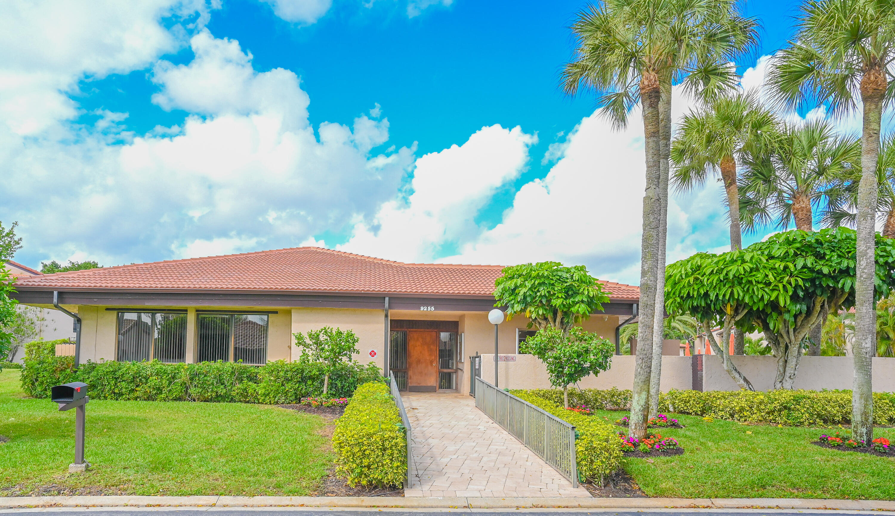 9259 Vista Del Lago, Unit 18J Boca Raton, FL 33428 - Photo 28 of 37 a front view of a house with a yard and potted plants