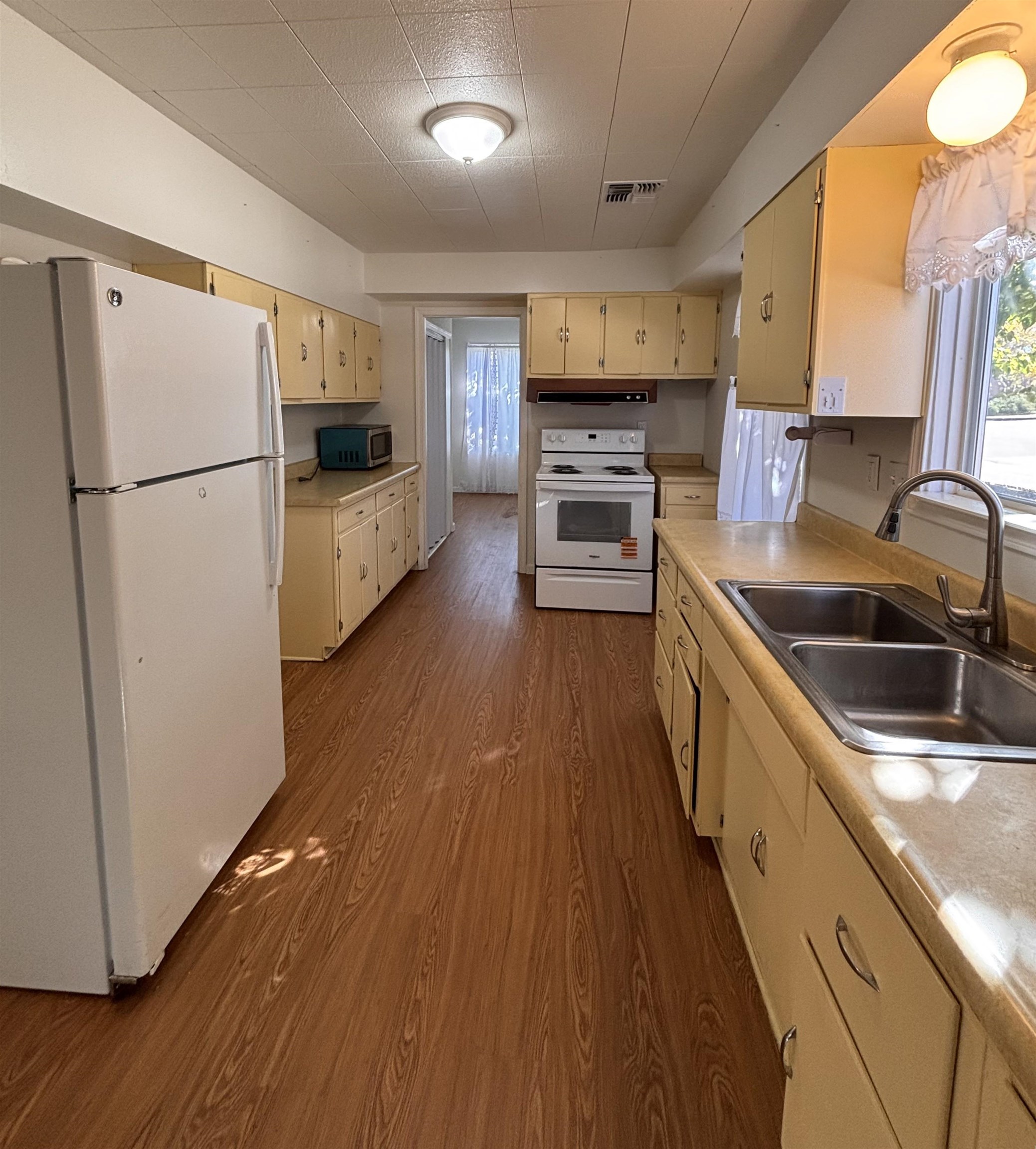 137 East Payne Street, Unit 5 Independence, CA 93526 - Photo 3 of 11 a kitchen with granite countertop a refrigerator a sink dishwasher and a stove with wooden floor