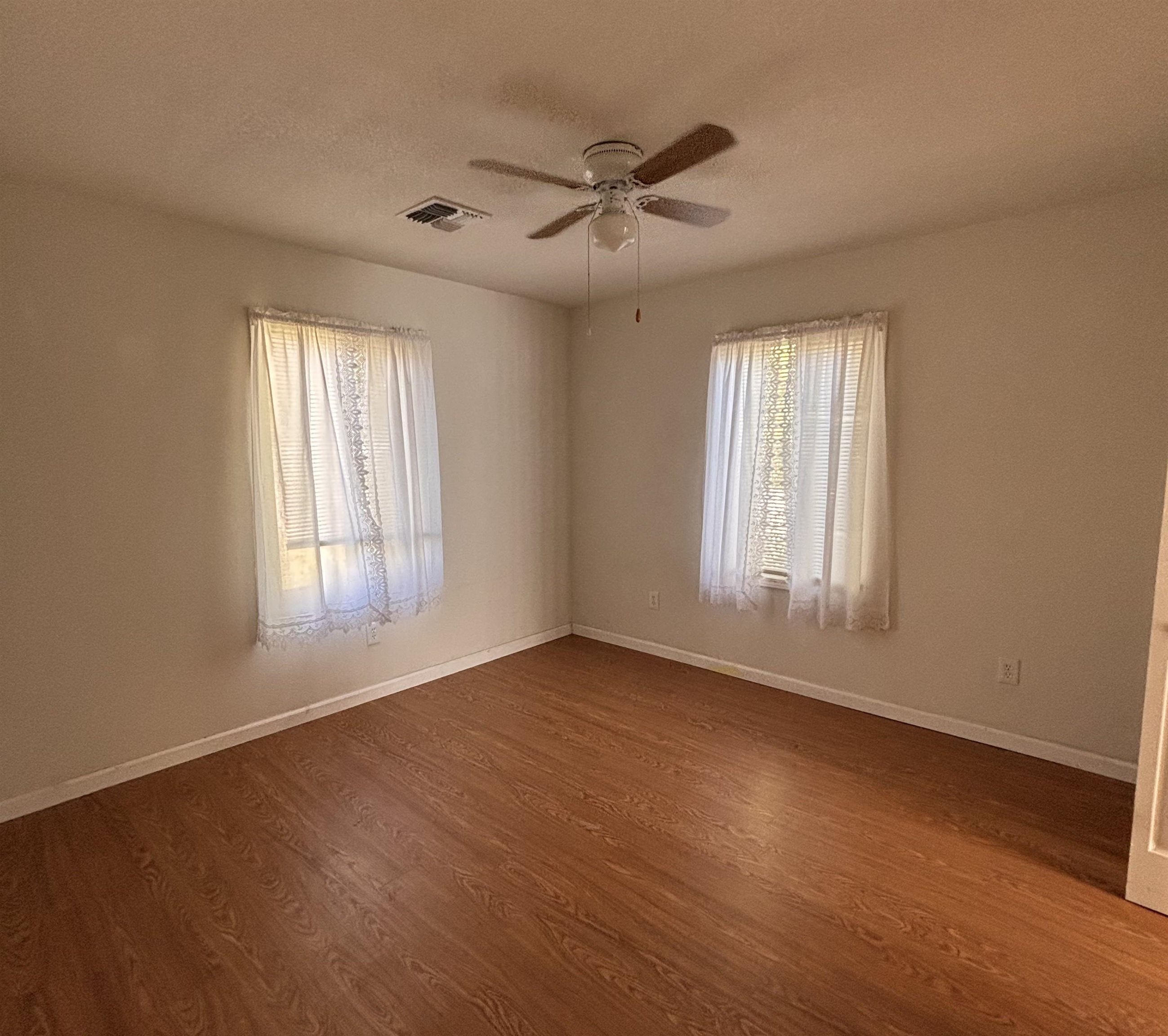 137 East Payne Street, Unit 5 Independence, CA 93526 - Photo 4 of 11 an empty room with wooden floor fan and windows