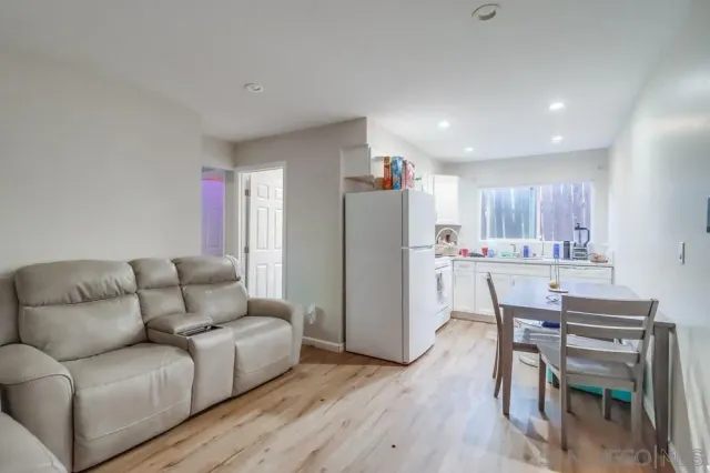 a living room with stainless steel appliances furniture and a wooden floor