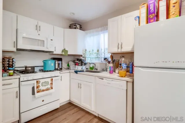a kitchen with white cabinets and white appliances