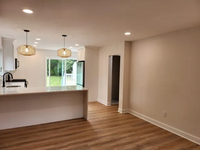 a view of an empty room with wooden floor fireplace and a window