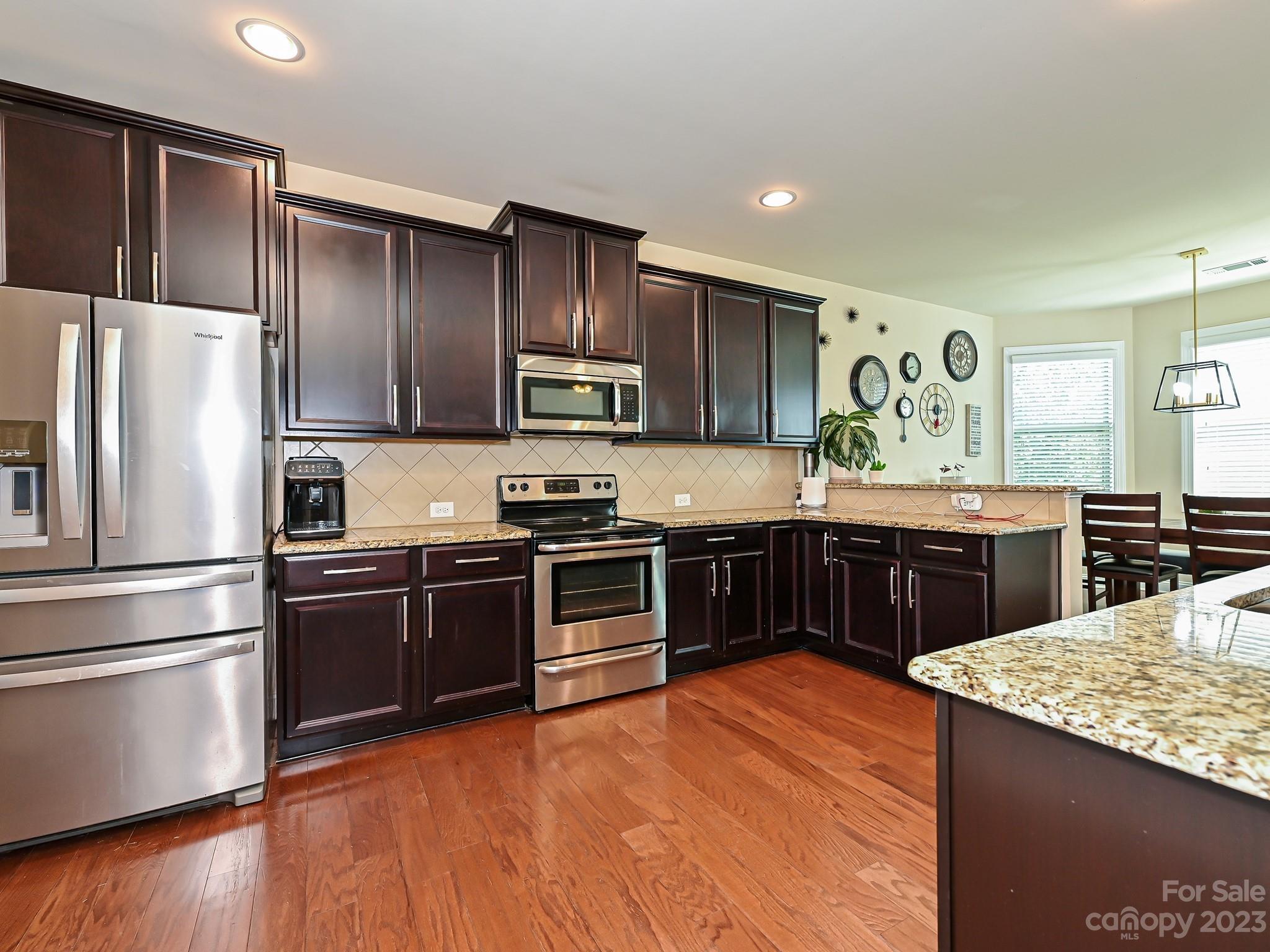 1012 Thorndale Road Indian Trail, NC 28079 - Photo 11 of 36 a kitchen with stainless steel appliances kitchen island granite countertop a stove a sink and a refrigerator