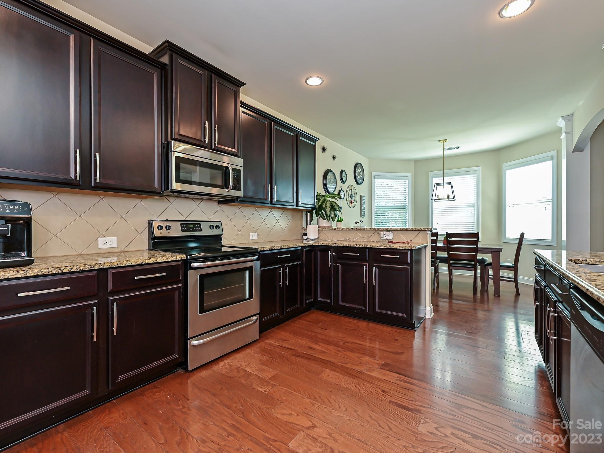 1012 Thorndale Road Indian Trail, NC 28079 - Photo 12 of 36 a kitchen with stainless steel appliances granite countertop wooden cabinets a stove top oven a sink and dishwasher