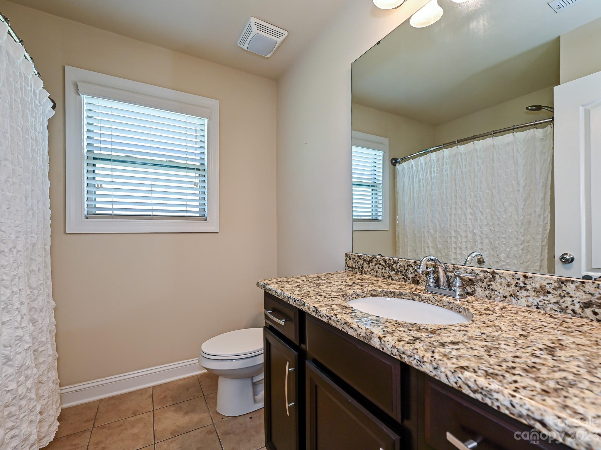 1012 Thorndale Road Indian Trail, NC 28079 - Photo 28 of 36 a bathroom with a granite countertop sink a toilet and a mirror