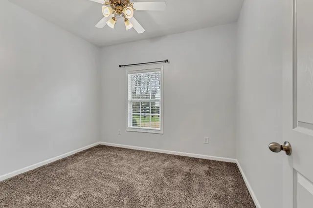an empty room with a chandelier fan and windows