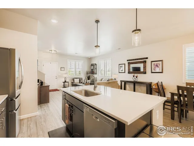 a kitchen with stainless steel appliances a sink a stove a refrigerator a center island a dining table and chairs