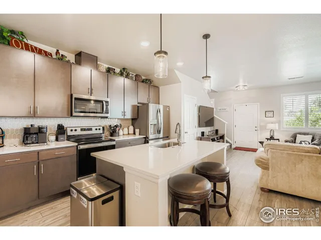 a kitchen with stainless steel appliances kitchen island granite countertop a sink dishwasher a stove a microwave oven a refrigerator with island and chairs