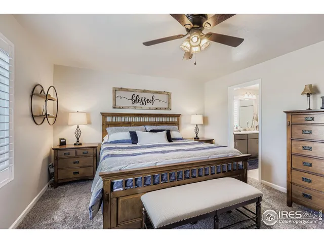 a bedroom with a bed a dresser with chair and window