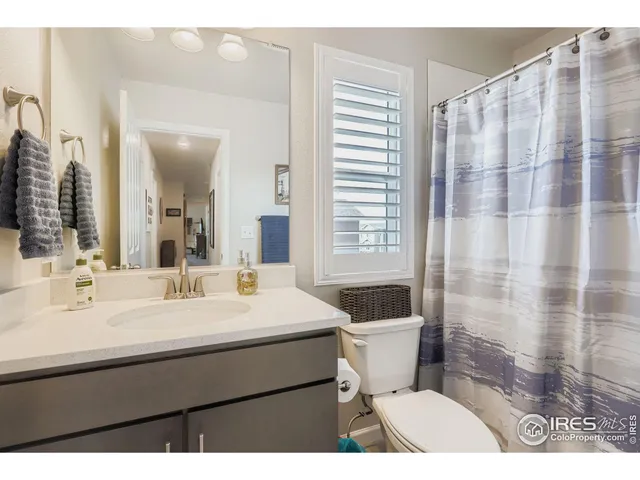 a bathroom with a sink a toilet a mirror and shower curtain