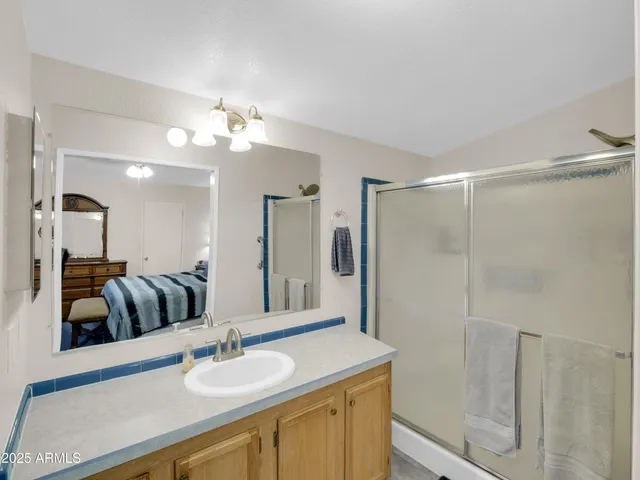a bathroom with a granite countertop sink a mirror and shower