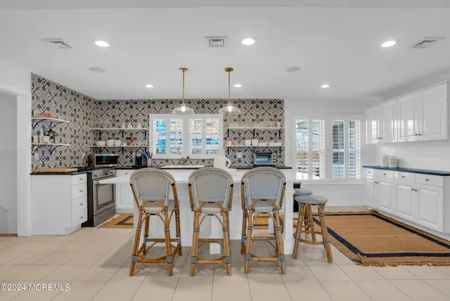 a kitchen with stainless steel appliances granite countertop a table chairs sink and cabinets