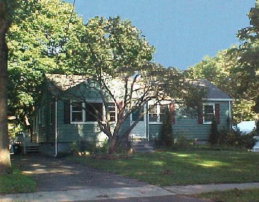 a front view of a house with a garden and trees