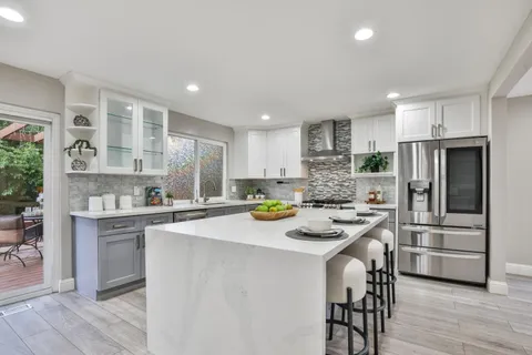 a kitchen with stainless steel appliances a refrigerator a sink dishwasher a oven with white cabinets and wooden floor