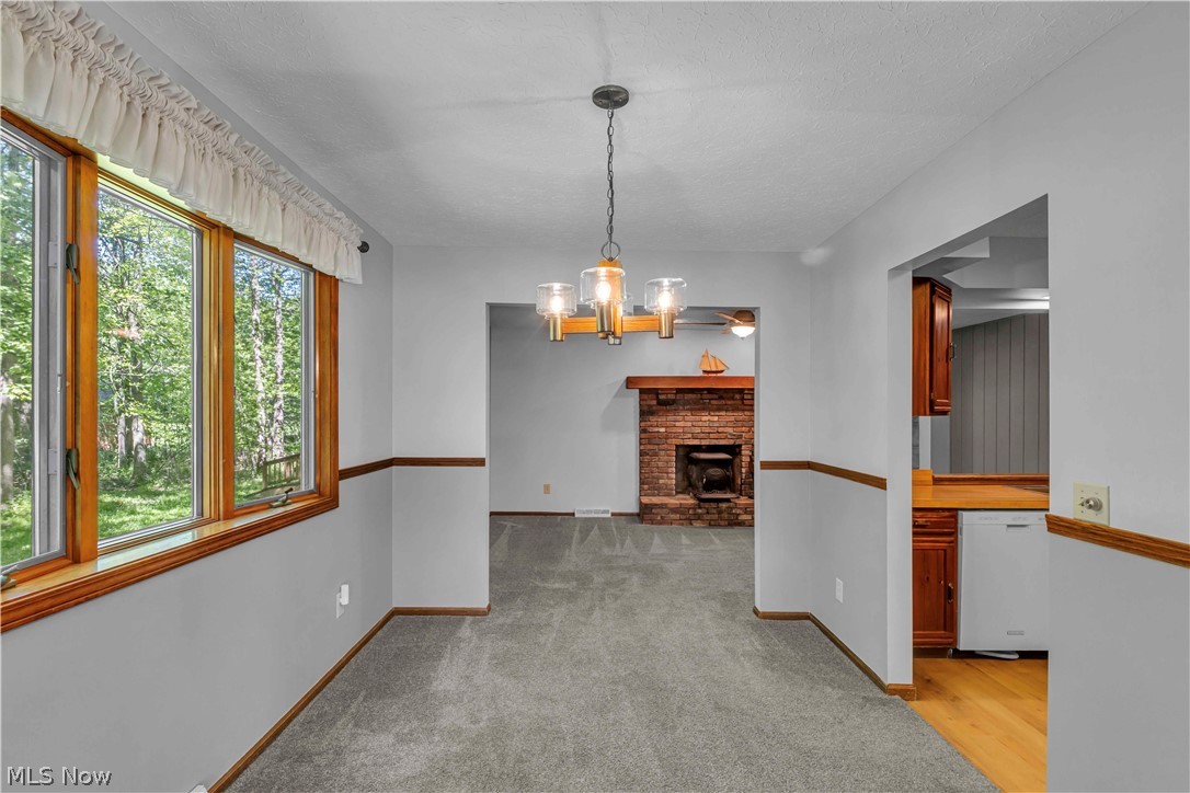 6635 Taylor Road Painesville, OH 44077 - Photo 21 of 41 Dining area featuring a contemporary chandelier, wood-trimmed windows, light gray wall paint with wood chair rail, and carpeting