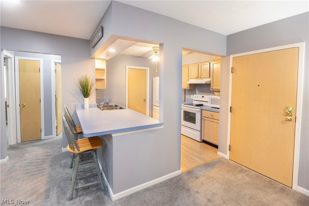 19510 Lorain Road, Unit 101 Cleveland, OH 44126 - Photo 7 of 24 Kitchen featuring Breakfast bar with white appliances, light wood-type flooring, light brown cabinets, sink, and ceiling fan