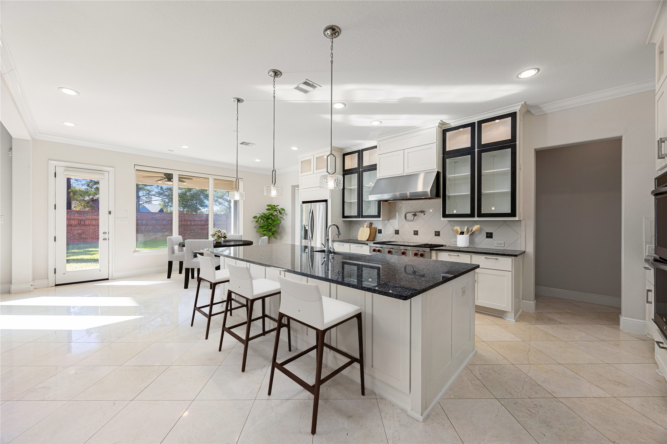 2102 Granite Brook Lane Katy, TX 77494 - Photo 11 of 39 This kitchen is truly a chef’s dream! Featuring an oversized granite island with breakfast bar seating, sleek stainless steel appliances, custom cabinetry with glass accents, a modern tile backsplash, pendant and recessed lighting, and a spacious open layout overlooking the family room, perfect for cooking, entertaining, and gathering with loved ones. *Virtually Staged