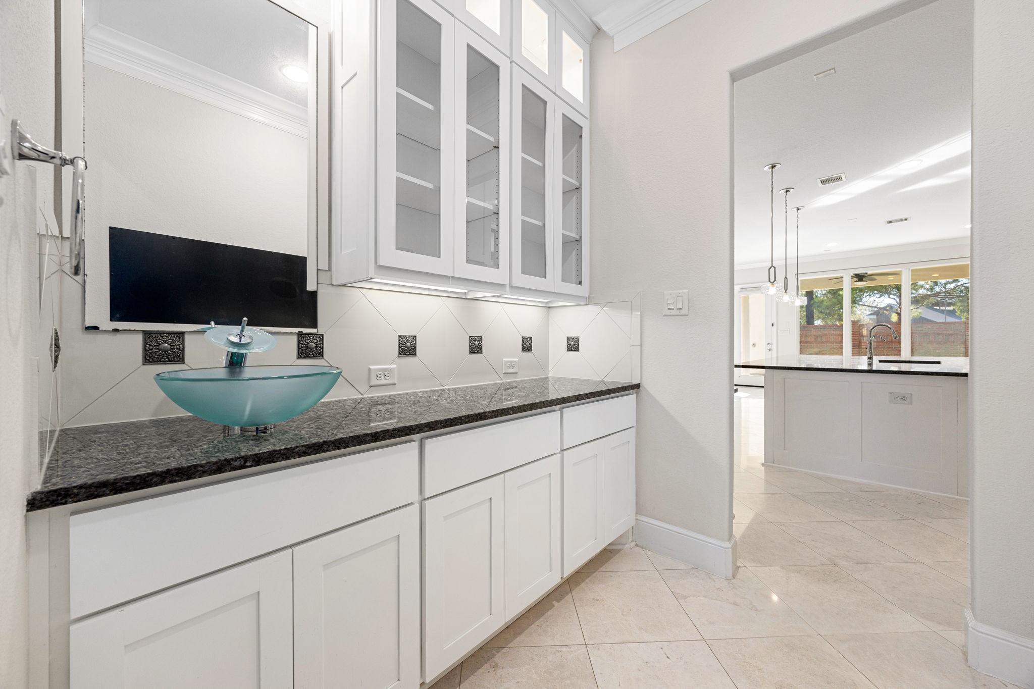 2102 Granite Brook Lane Katy, TX 77494 - Photo 13 of 39 Conveniently located between the formal dining room and kitchen, this elegant butler’s pantry offers additional counter space, custom cabinetry with glass fronts, granite countertops, and a modern vessel sink, perfect for serving, storage, or entertaining guests.