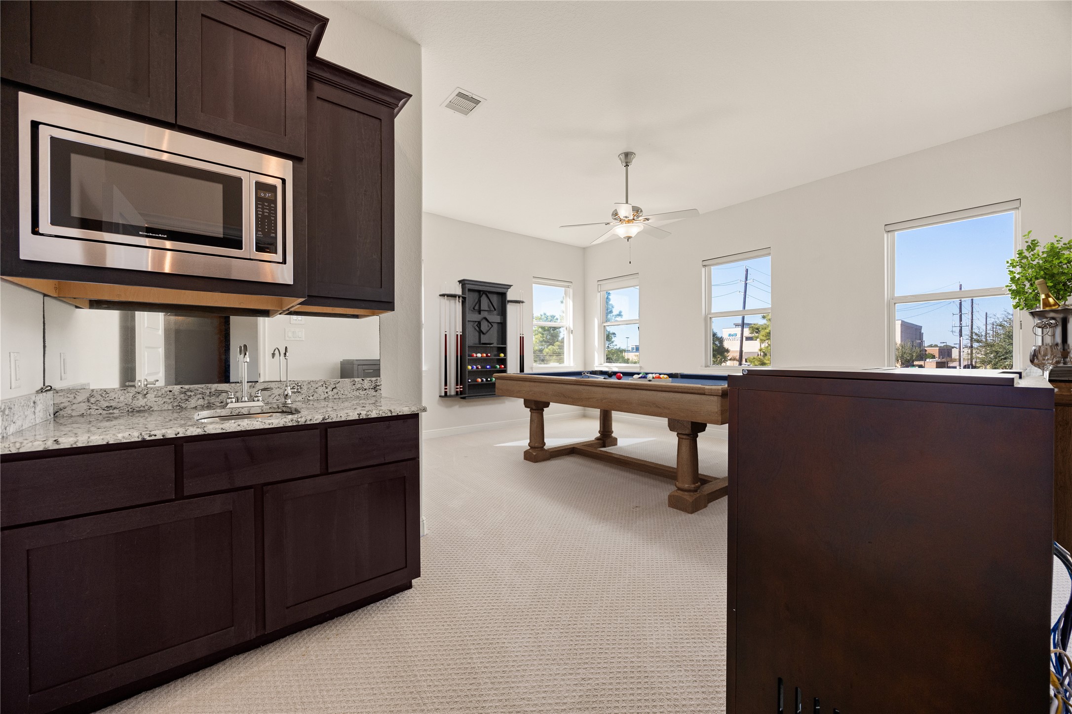 2102 Granite Brook Lane Katy, TX 77494 - Photo 26 of 39 Upstairs game room complete with a built-in wet bar featuring granite countertops, dark cabinetry, and a stainless steel microwave, perfect for entertaining family and friends! *Virtually Staged