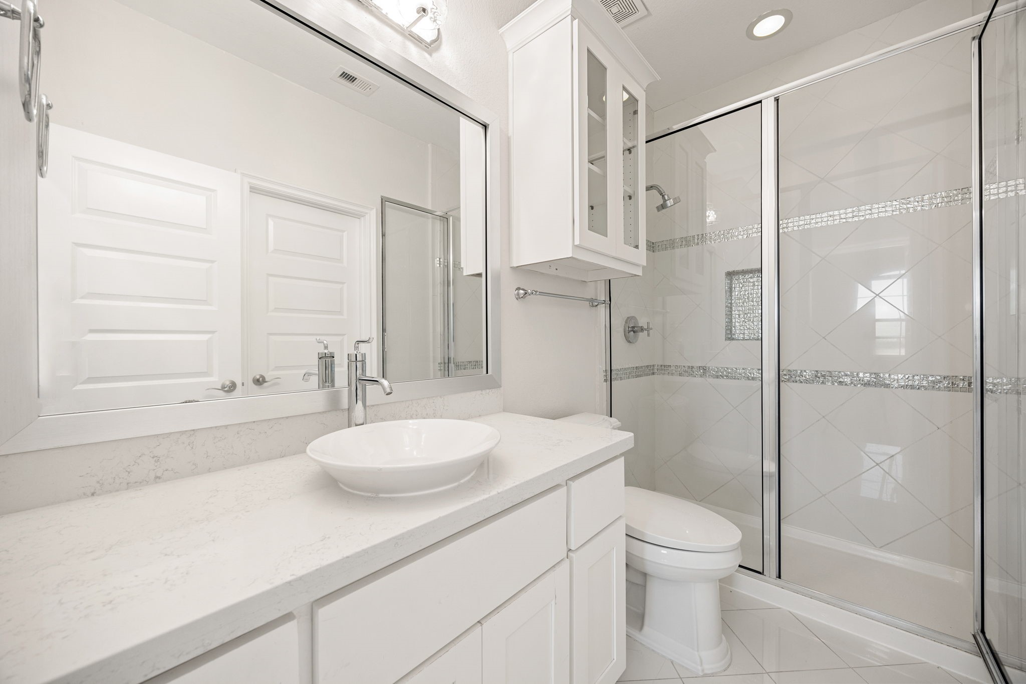 2102 Granite Brook Lane Katy, TX 77494 - Photo 31 of 39 Beautifully updated secondary bath offering a frameless glass shower with silver mosaic detailing, quartz countertops, contemporary lighting, and crisp white cabinetry.