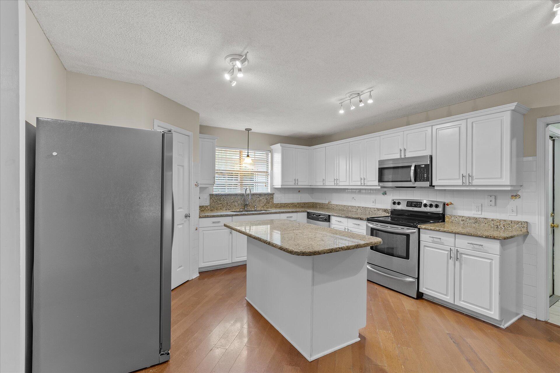 2723 Rambler Court Navarre, FL 32566 - Photo 12 of 40 a kitchen with stainless steel appliances granite countertop a refrigerator a sink dishwasher a stove top oven a refrigerator and white cabinets with wooden floor
