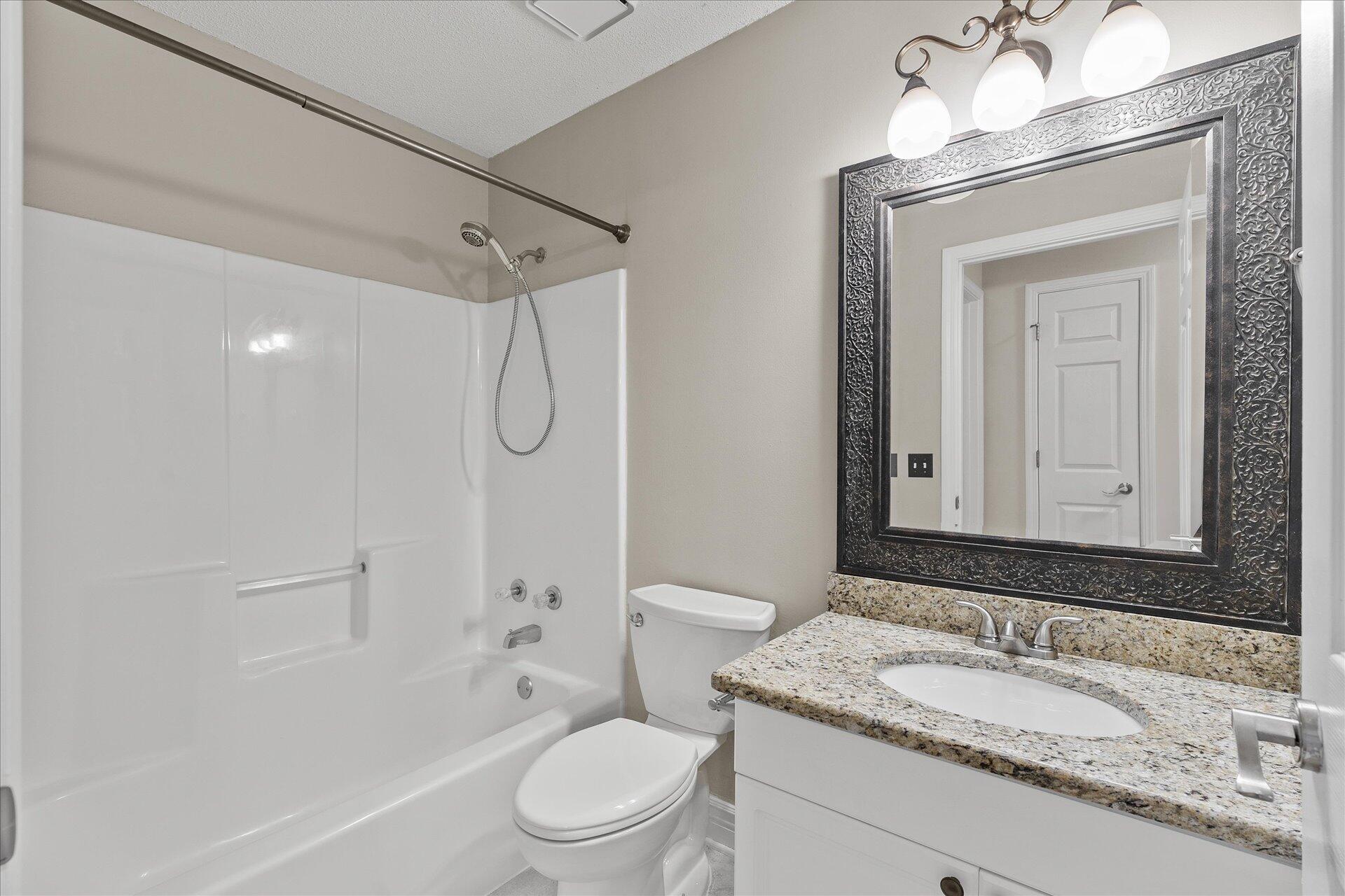 2723 Rambler Court Navarre, FL 32566 - Photo 32 of 40 a bathroom with a granite countertop sink toilet a mirror and shower