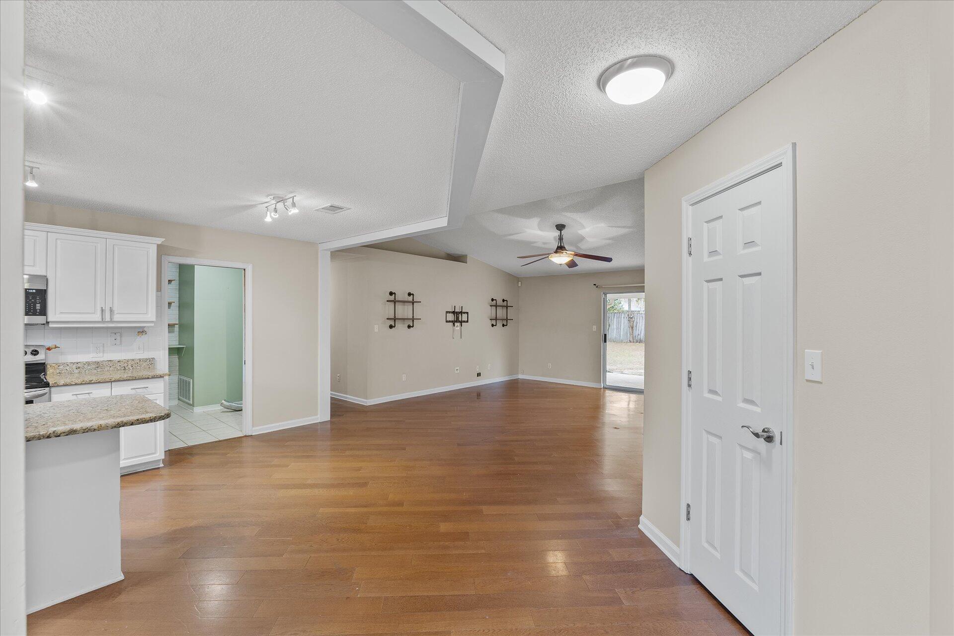 2723 Rambler Court Navarre, FL 32566 - Photo 7 of 40 a view of an empty room and kitchen with wooden floor