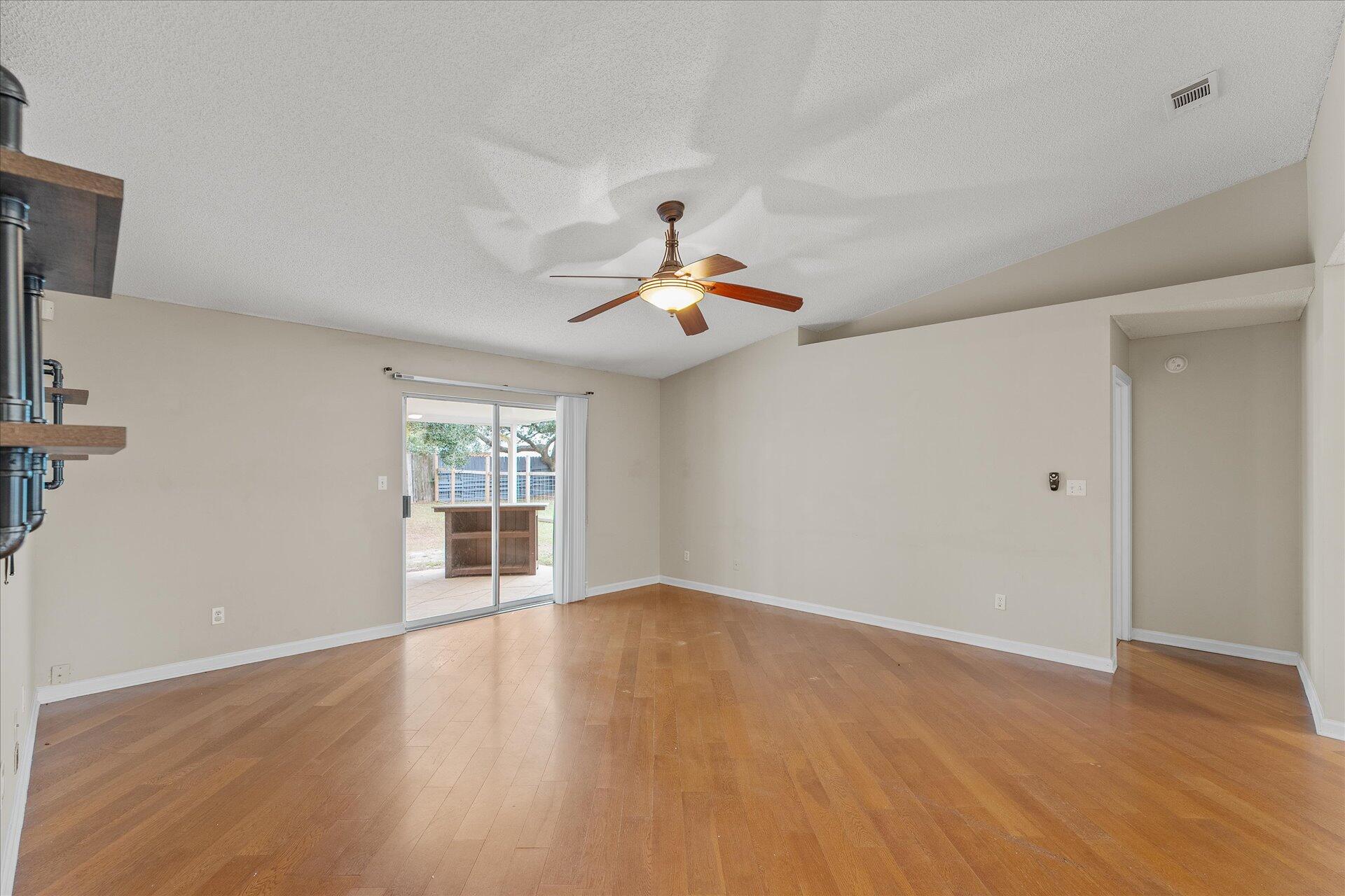 2723 Rambler Court Navarre, FL 32566 - Photo 9 of 40 a view of an empty room with wooden floor and a window