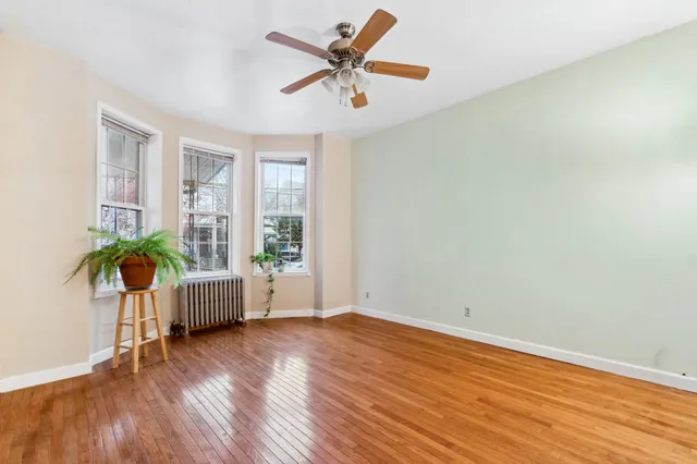 a view of an empty room with a window and wooden floor