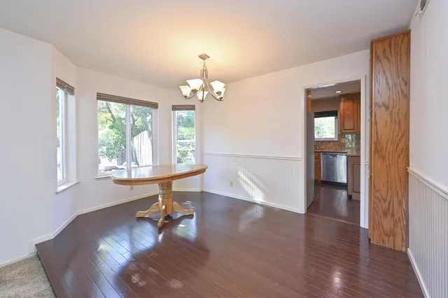 a dining room with wooden floor a chandelier a wooden table and chairs