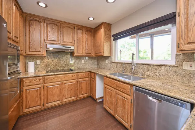 a kitchen with stainless steel appliances granite countertop a sink a stove and cabinets