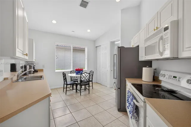 a kitchen with stainless steel appliances granite countertop a dining table and chairs