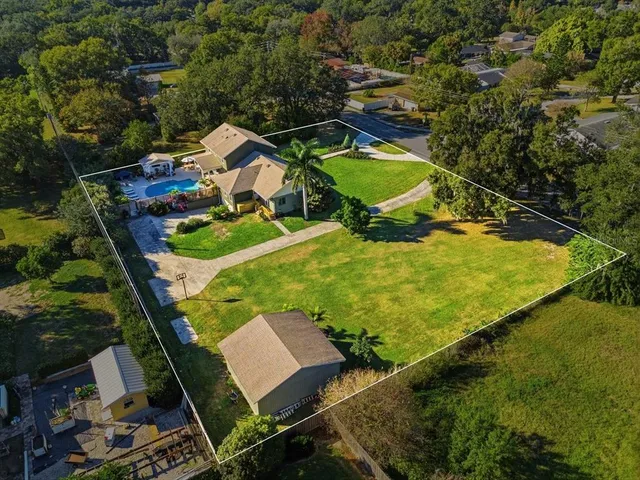 an aerial view of a house with swimming pool and large trees
