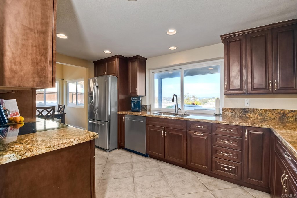 2754 Olympia Drive Carlsbad, CA 92010 - Photo 6 of 35 a kitchen with stainless steel appliances granite countertop wooden cabinets a refrigerator and a sink