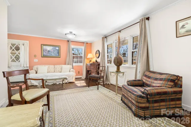 a living room with furniture a clock on wall and a window