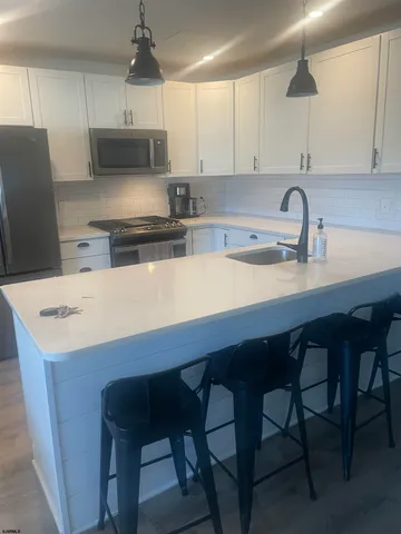 a kitchen with stainless steel appliances a white table chairs and a refrigerator